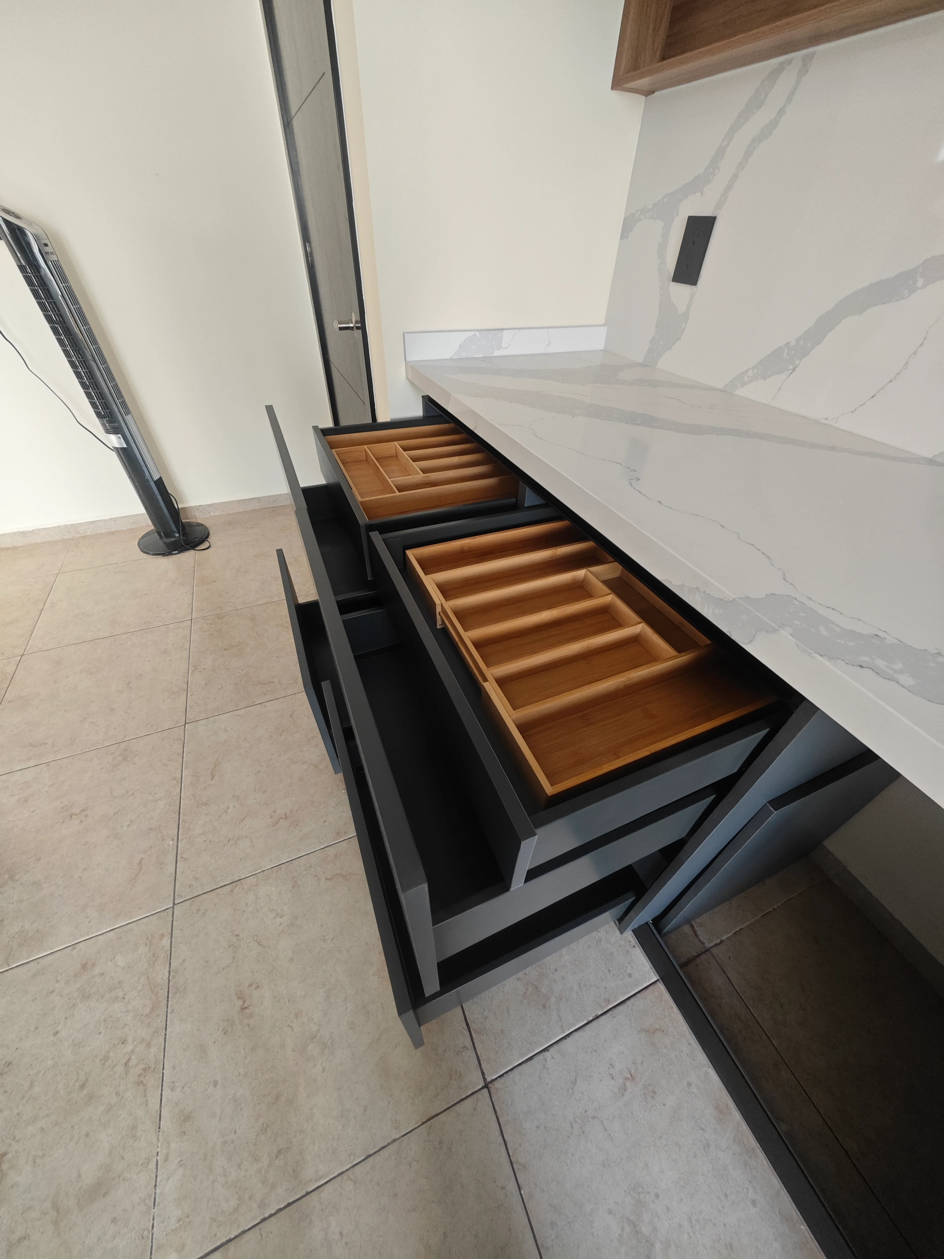 Detalle real de un cajón abierto con organizador en madera en una cocina Olivewood